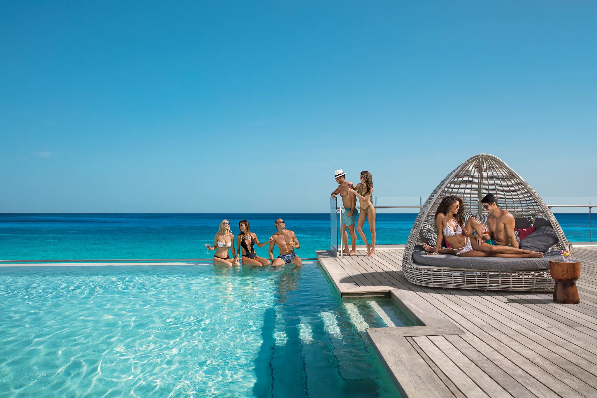 Group of friends enjoying the infinity pool overlooking the ocean at Breathless Montego Bay.