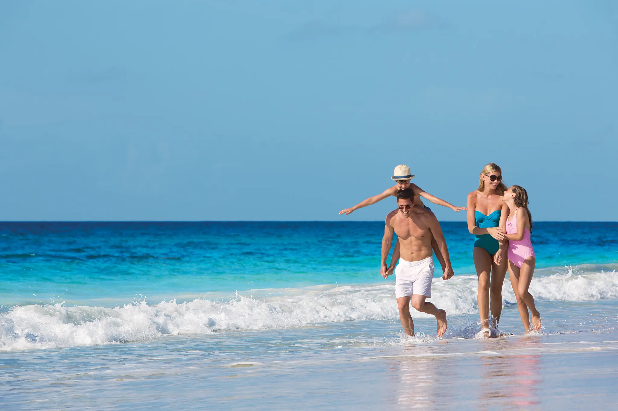 Family walking along the turquoise Caribbean shoreline at Dreams Jade Resort & Spa.